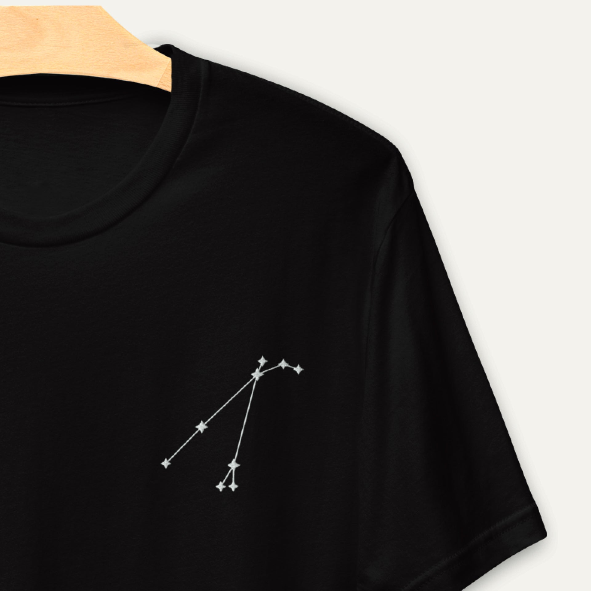 Close-up of the Constellation Tee, highlighting the delicate white embroidery of a star sign constellation on the t-shirt's black fabric.