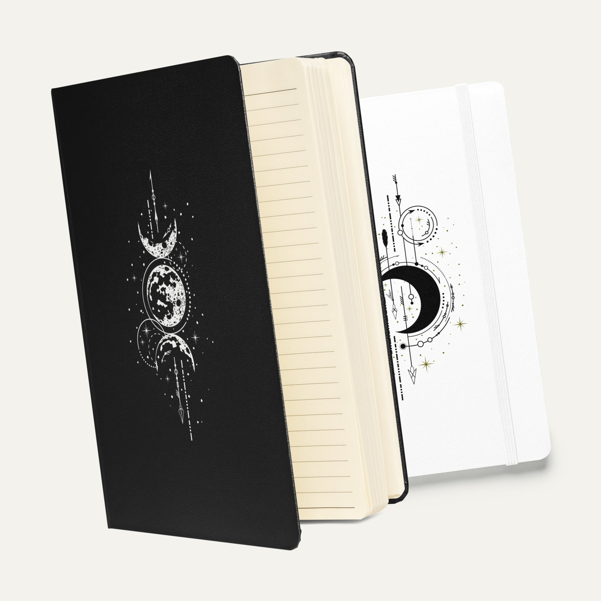 Black and white hardbound Phases Dream Journals with elegant celestial moon phase designs, shown open to reveal lined pages.